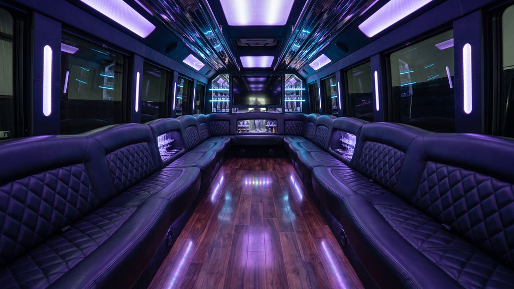 Interior of a luxury party bus with leather seating and purple LED lighting